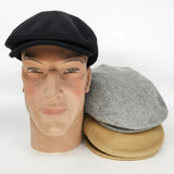 Mannequin head with black, gray, and camel flat caps on a white background
