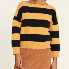 Woman wearing a black and yellow striped sweater with a beige background