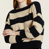 Woman wearing a black and creme striped sweater on a plain background