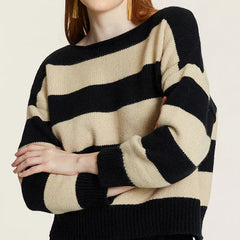 Woman wearing a black and creme striped sweater on a plain background