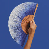 Hand holding a gradient fan against a blue background
