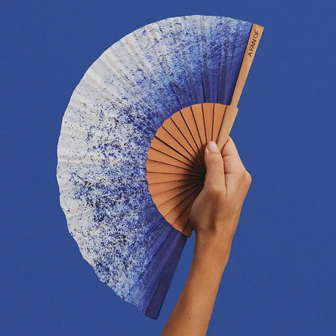 Hand holding a gradient fan against a blue background