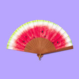 Handheld fan with watermelon design on a purple background